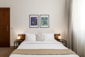 um quarto com uma cama branca e duas fotografias na parede em Livingville The Two-Fifty em Cairo