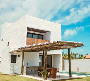 a white house with a table and an umbrella at Casa Pitanga - 150 mts do mar in Pôrto de Pedras