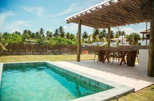 a swimming pool with a table and a dining area at Casa Pitanga - 150 mts do mar in Pôrto de Pedras