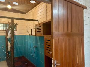 a bathroom with a shower with a large wooden cabinet at Maison meublée « valiha » in Hell-Ville