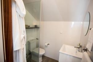 La salle de bains blanche est pourvue de toilettes et d'un lavabo. dans l'établissement Amazing modern house on the sea!, à Ferrel