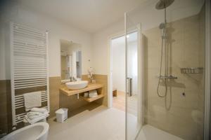 La salle de bains blanche est pourvue d'un lavabo et d'une douche. dans l'établissement Hotel Ristorante Da Tullio, à Tarzo