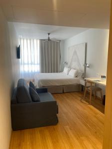 1 dormitorio con cama, sofá y mesa en Talayot - Adults Only, en Cala Millor