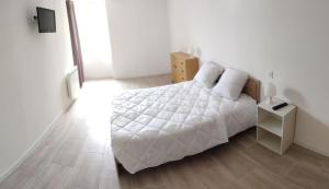 una camera con letto bianco e pavimento in legno di Gîte de saint pabut a Pluherlin