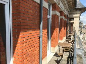 eine rote Backsteinmauer mit Fenstern und Bänken an einem Gebäude in der Unterkunft Le duplex de Talleyrand Hyper Centre in Reims