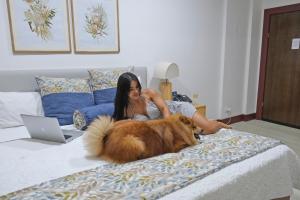 Paradise Bay Hotel Boutique في هيرادورا: امرأة جالسة على سرير مع كلب
