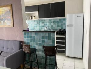 een keuken met een koelkast en 2 barkrukken bij Apartamento aconchegante perto do Shopping Iguatemi in Votorantim