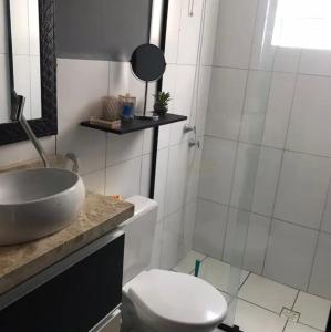 een witte badkamer met een wastafel en een toilet bij Apartamento aconchegante perto do Shopping Iguatemi in Votorantim