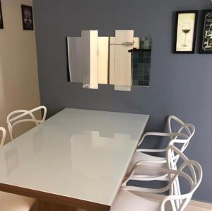 een witte eettafel met witte stoelen bij Apartamento aconchegante perto do Shopping Iguatemi in Votorantim