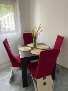une table à manger avec des chaises rouges et un vase de fleurs dans l'établissement Apartments Arina, à Krasići