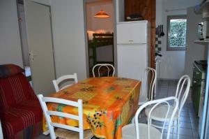 een keuken met een tafel en stoelen en een koelkast bij Résidence ILE DES PECHEURS - Maisons & Villas pour 6 Personnes 34 in Port Leucate