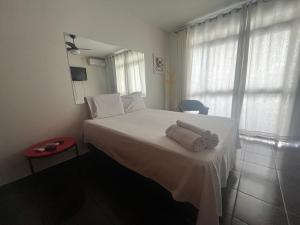 Un dormitorio con una cama blanca con toallas. en Suíte espaçosa! Ar, Tv e banheiro privativo!, en Goiânia