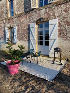 een patio met een tafel en stoelen naast een gebouw bij Le Colibri - Domaine de la Houblette in Challans