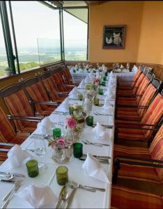 una mesa larga en una habitación con mesas y sillas blancas en Panoramahotel Steirerland, en Kitzeck im Sausal