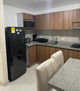 La cuisine est équipée d'un réfrigérateur noir et de placards en bois. dans l'établissement Espectacular casa vacacional con garaje en Pereira, à Pereira