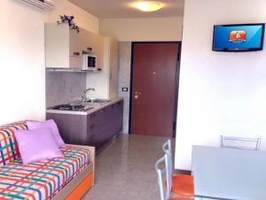 een woonkamer met een bank en een keuken bij Enjoy poolside comfort - Beahost Rentals in Bibione