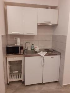 cocina con armarios blancos, fregadero y microondas en Studio Apartment Ana, en Zadar