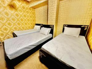 Jhelum Khan Hotel في Jhelum: سريرين في غرفة بجدران صفراء