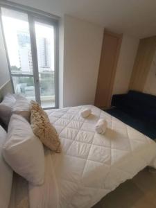 een groot wit bed in een kamer met een raam bij Apartamento cerca a la Playa 5-01 in Gaira