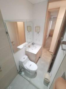 een badkamer met een toilet, een wastafel en een spiegel bij Apartamento cerca a la Playa 5-01 in Gaira