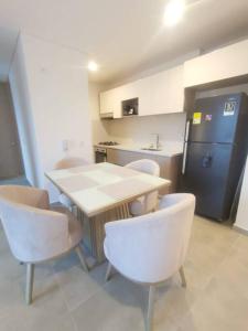 een keuken met een tafel en stoelen en een koelkast bij Apartamento cerca a la Playa 5-01 in Gaira
