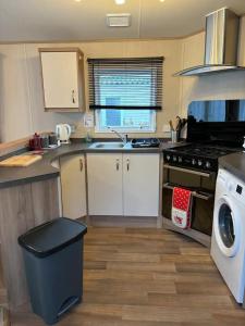a kitchen with a sink and a stove top oven at Woodpecker lodge, Camelot Holiday Park, CA6 5SZ in Carlisle