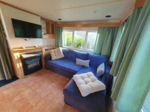 sala de estar con sofá azul y TV en Camping du Lac, en Égletons