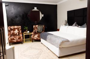 a bedroom with a bed and two chairs and a mirror at Toriso Hotels Group in Nelspruit