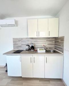 - une cuisine avec des placards blancs et un évier dans l'établissement Apartments Vero 2-4 Personen, à Orebić