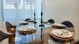una mesa de cristal con sillas y platos. en MODERNO APARTAMENTO AMBUELADO TOTALMENTE NUEVO., en Bonao