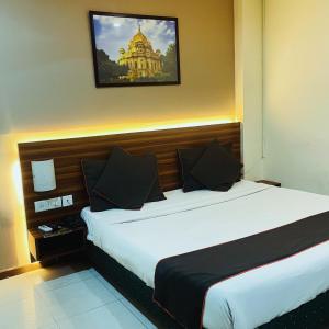 Royal Presidency Inn في لاكناو: غرفة فندق بسرير وصورة على الحائط