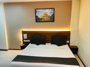 Royal Presidency Inn في لاكناو: غرفة نوم بسرير مع صورة على الحائط