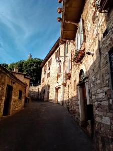 eine Gasse in einem alten Steingebäude mit einem Turm in der Unterkunft Studio dell'Arco - Assisi in Assisi