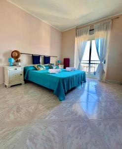 - une chambre avec un lit bleu et une grande fenêtre dans l'établissement Onda Blu Apartment, à Pizzo