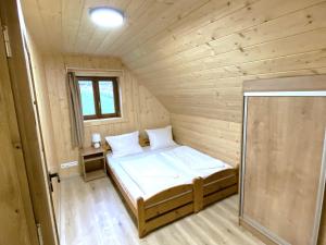 a small bedroom with a bed in a wooden room at Chata Starý Mlyn in Habovka
