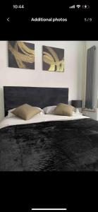 a bedroom with a large black bed with two pillows at Luxury king en-suite room in Peterborough