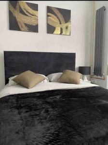 a bedroom with a large bed with a black headboard at Luxury king en-suite room in Peterborough