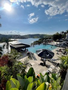 a large swimming pool with umbrellas and a body of water at Pousada Villa Shalom in Igaratá