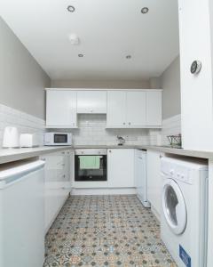 a kitchen with white cabinets and a washer and dryer at Belfast Quarters: Modern City Centre Hub 3 Bed in Belfast