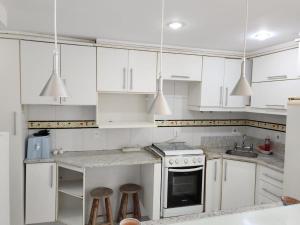uma cozinha branca com armários brancos e electrodomésticos brancos em Prainha- Cobertura 3 Quartos 70 metros da praia! em Arraial do Cabo