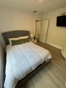 1 dormitorio con 1 cama grande con sábanas blancas y almohadas verdes en Queen bedroom in best Location! - Private Parking, Laundry and Drop Off Lugagge, en Miami