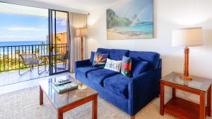 a living room with a blue couch and a balcony at Maui Westside Presents: Kaanapali Shores 733 Stunning Ocean Views NEW LISTING in Lahaina