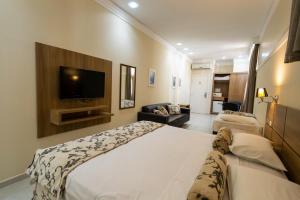 um quarto de hotel com uma cama e uma televisão de ecrã plano em Wynn Batel em Curitiba