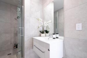 a bathroom with a white sink and a shower at Luxury 2 bed townhome in CBD in Christchurch +82 photos