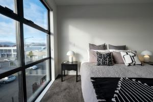 a bedroom with a bed and a large window at Luxury 2 bed townhome in CBD in Christchurch