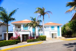 a white house with palm trees and a street at Casa Arcoíris: Espectacular casa en Cartagena con Acceso directo a la Playa in Cartagena de Indias