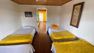 a room with three beds in it with a hallway at Hospedaje Campestre Araucarias in Santa Rosa de Cabal