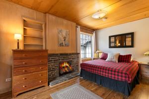ein Schlafzimmer mit einem Kamin und einem Bett mit einer Decke in der Unterkunft Elkhorn Lodge Vacation Rentals in Banff