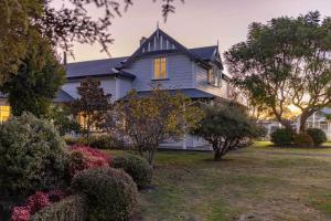 une maison bleue avec des fenêtres jaunes sur une cour dans l'établissement Havelock Homestead, à Havelock North