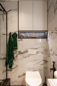 La salle de bains est pourvue de toilettes blanches et d'un mur en marbre. dans l'établissement Beautiful Designer Apartment in Riga center, à Riga